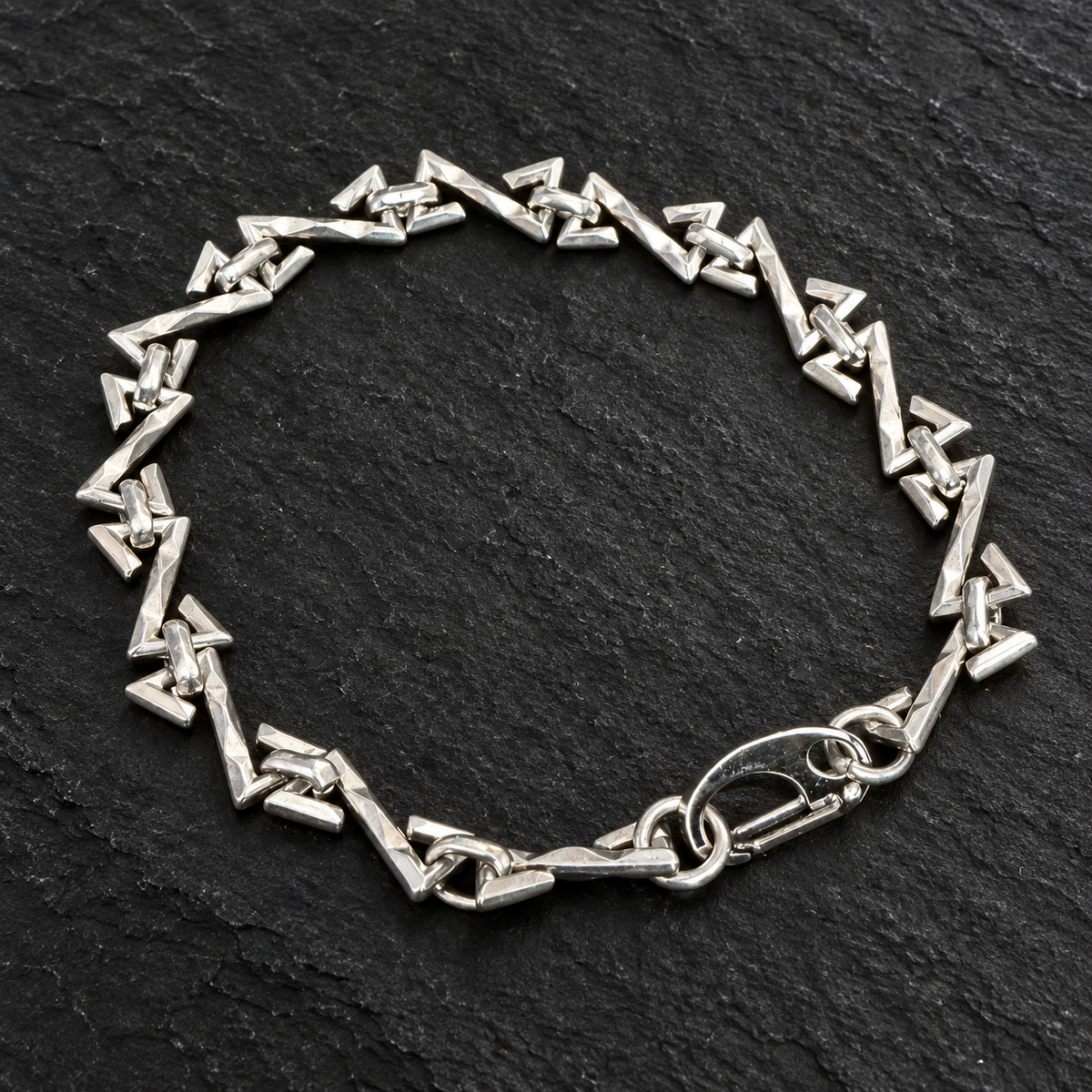 Bracelet chaîne à maillons triangulaires sur fond sombre