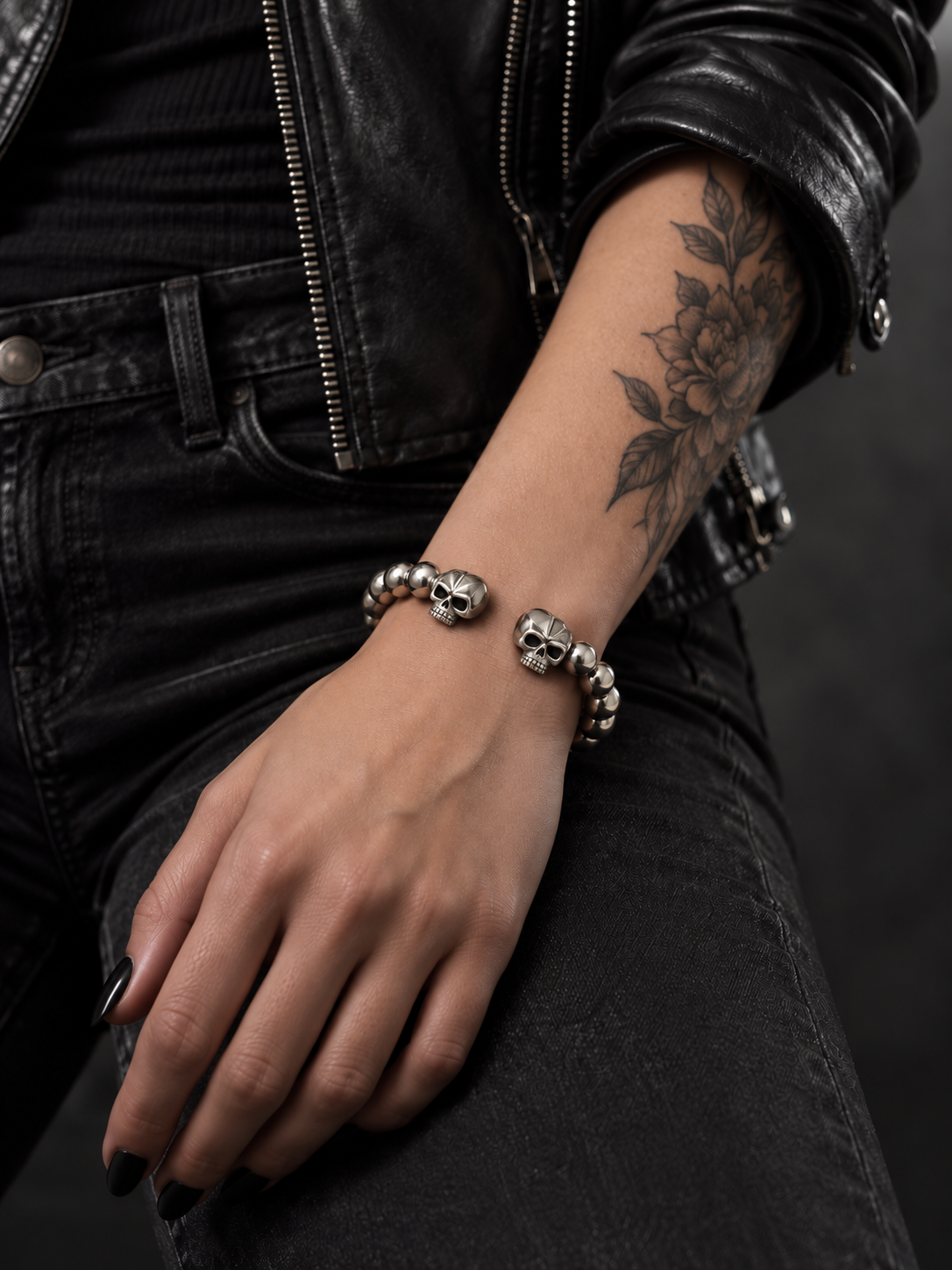 Bracelet jonc boules métalliques et deux crânes porté au poignet