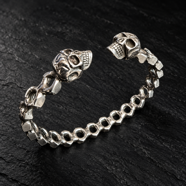 Bracelet jonc écrous ajourés et deux crânes — Une rangée sur fond sombre