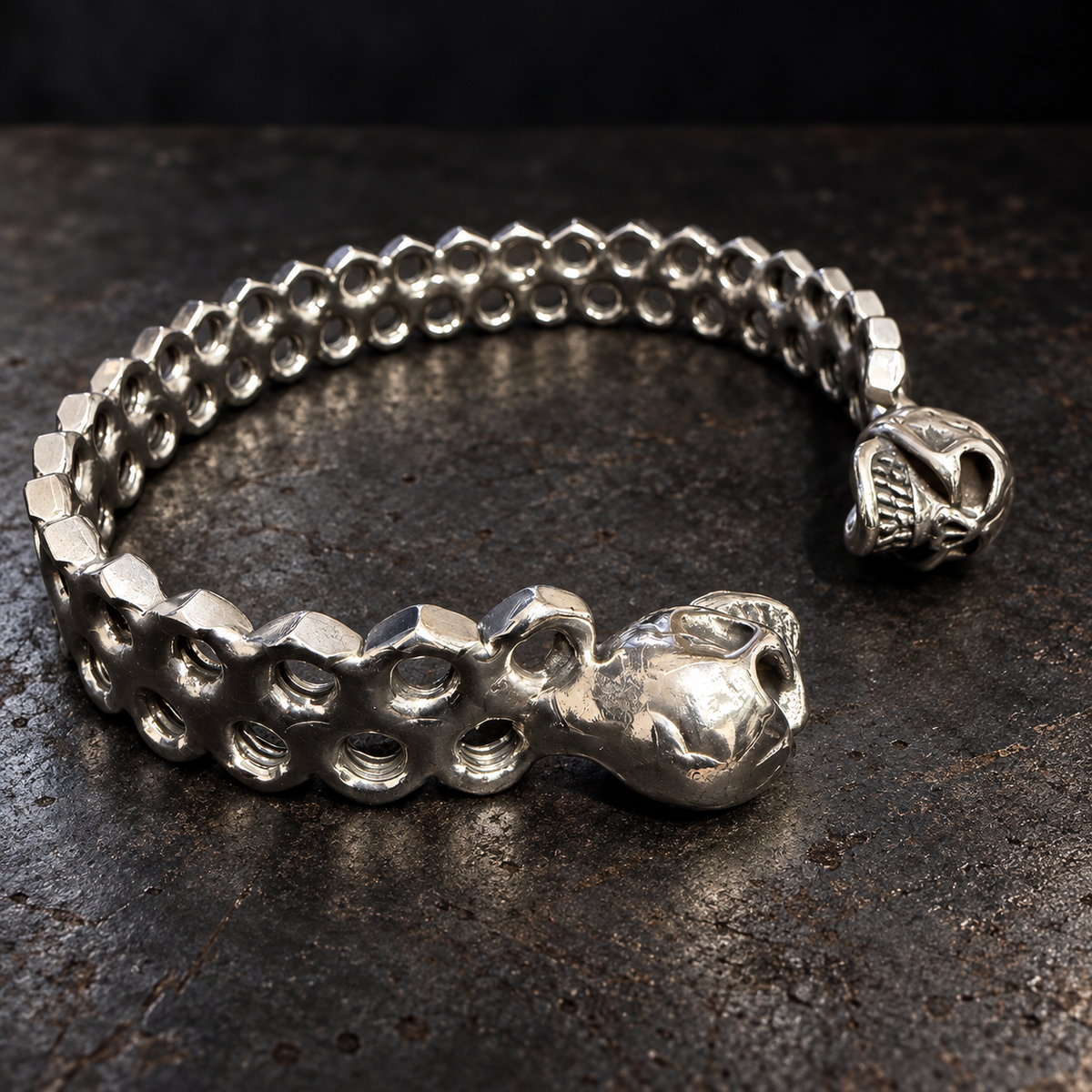 Bracelet jonc écrous et deux crânes sur une surface d’atelier sombre