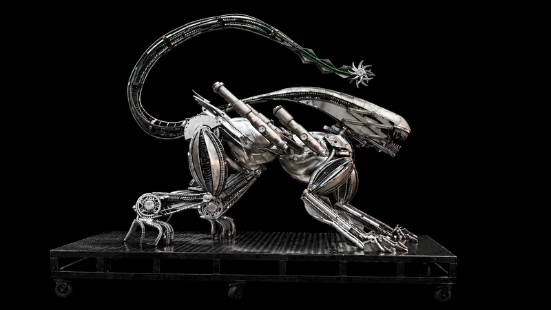Alien Mécanikus sur son socle à roulettes, photo originale sur fond noir