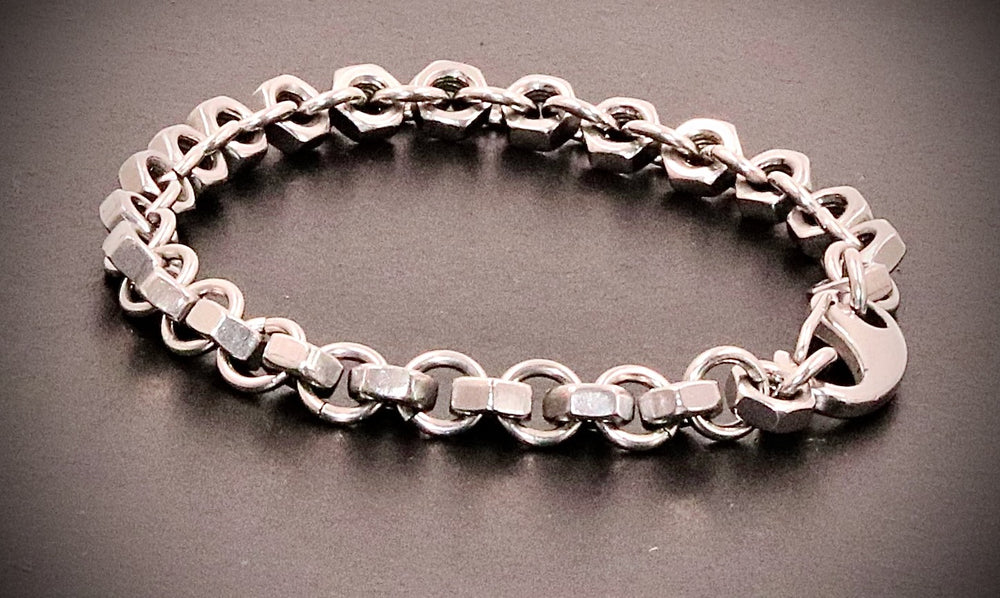 Bracelet composé d’écrous hexagonaux reliés par des anneaux, avec fermoir mousqueton — photographie originale