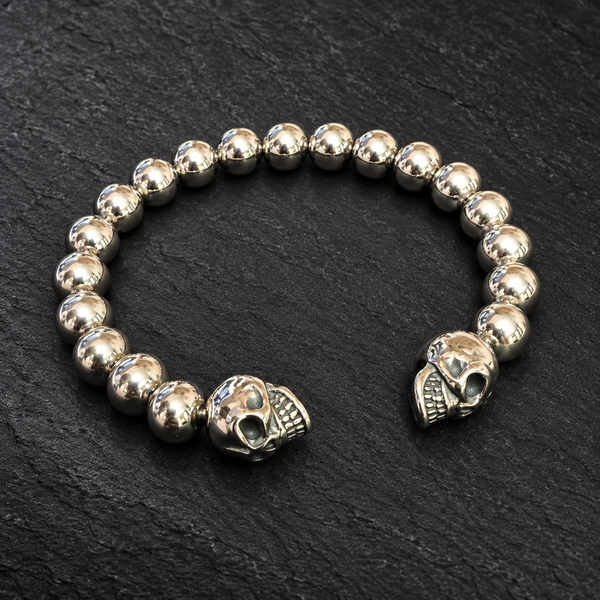 Bracelet jonc boules métalliques et deux crânes sur fond sombre