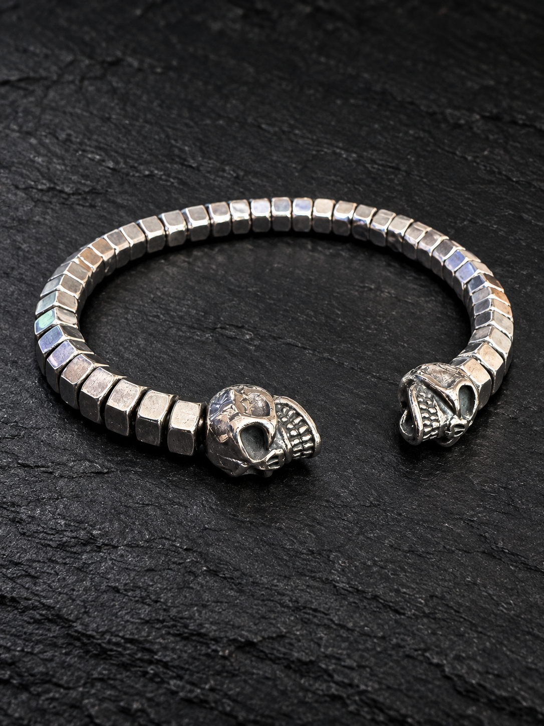 Bracelet jonc écrous alignés et deux crânes sur fond sombre