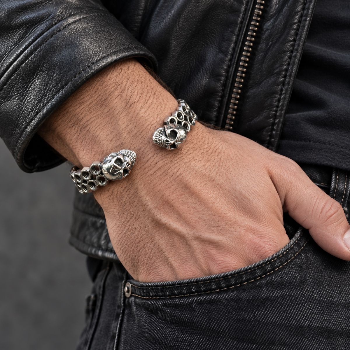 Bracelet jonc écrous et deux têtes de mort porté avec une veste en cuir noir