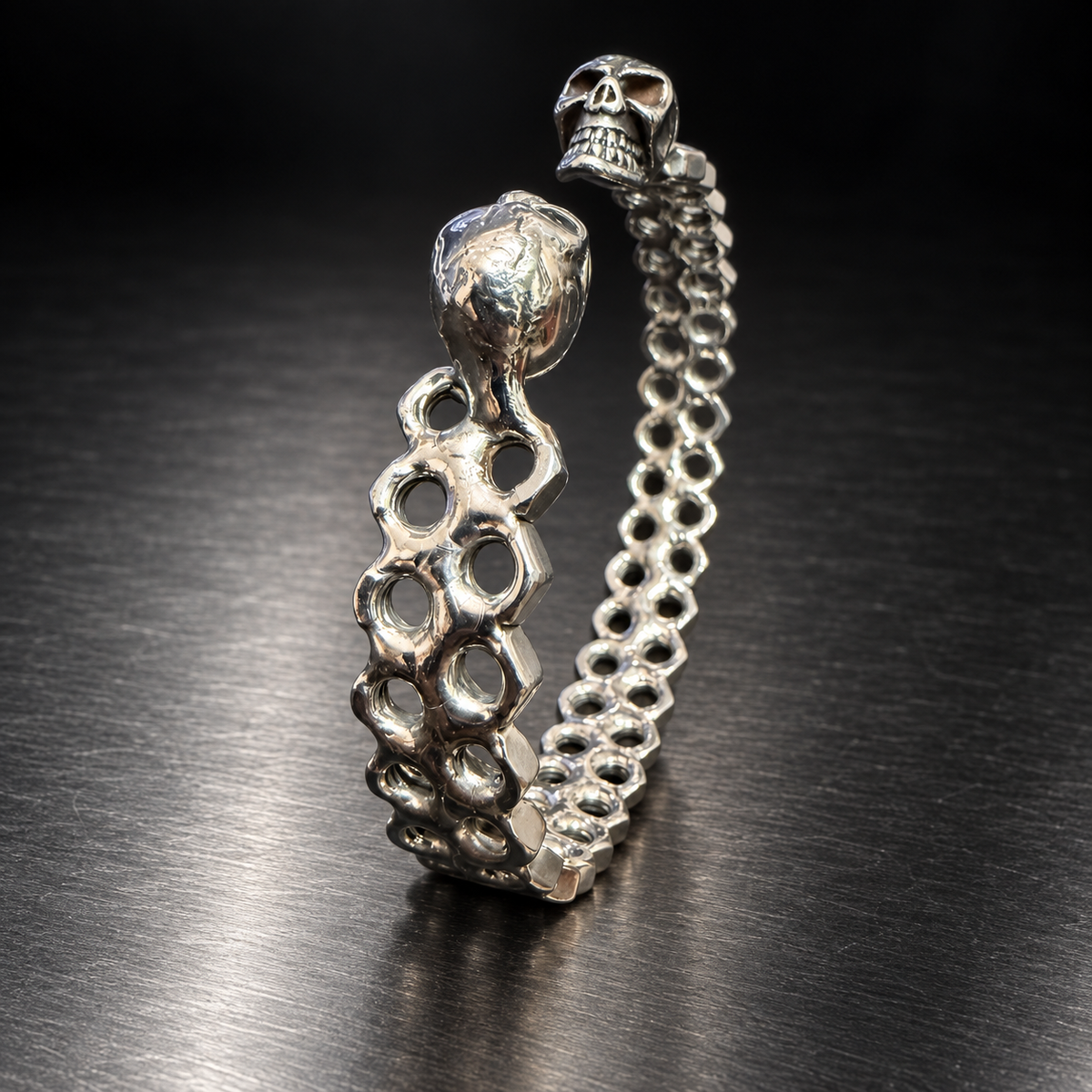 Bracelet jonc écrous et têtes de mort vu de profil sur acier sombre