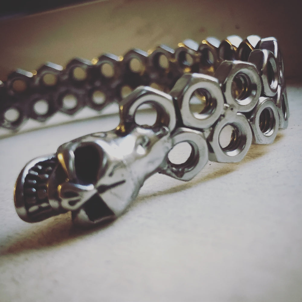 Détail d’un bracelet jonc à deux rangées d’écrous décalés et grande tête de mort à l’extrémité — photographie originale
