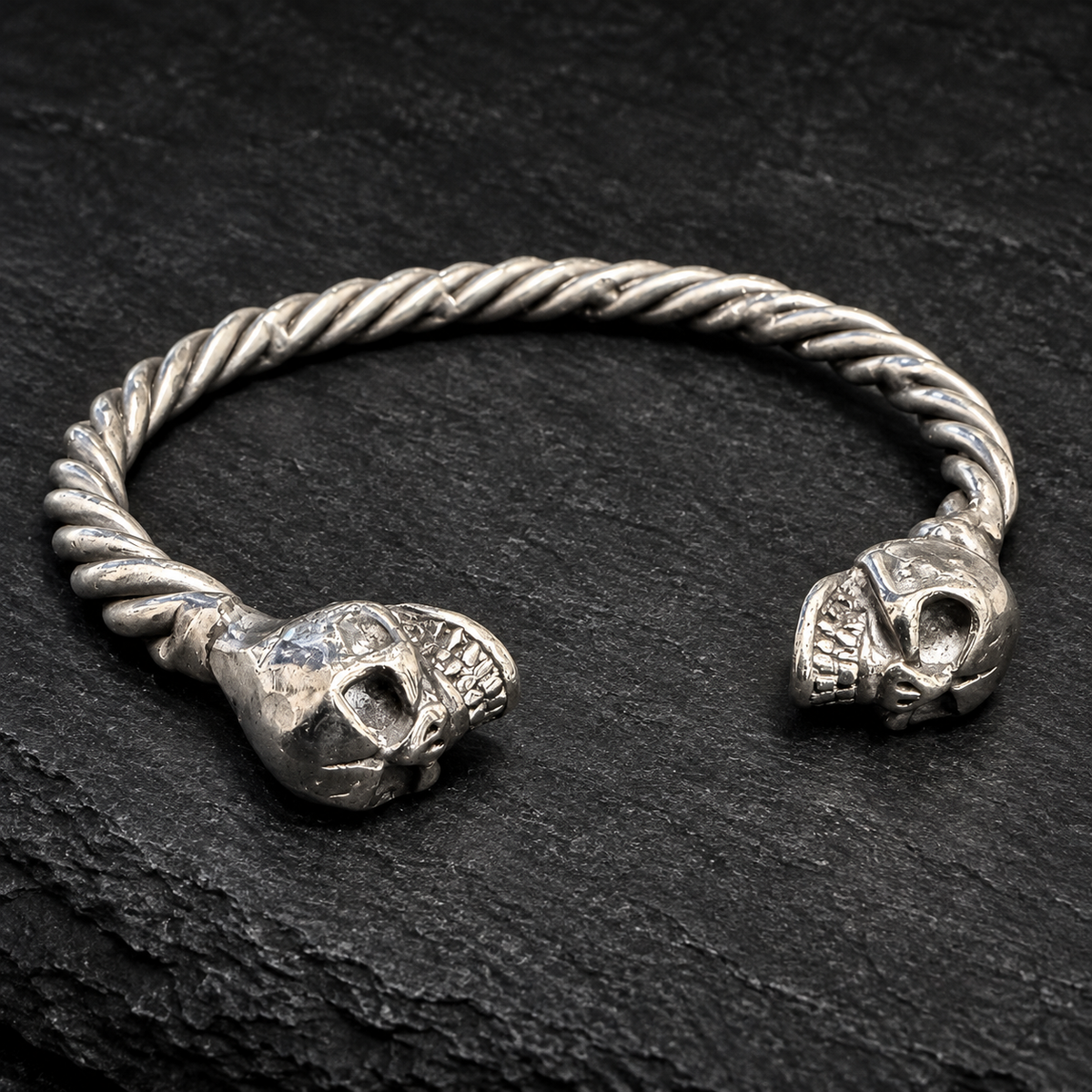 Bracelet jonc torsadé et deux têtes de mort sur fond sombre