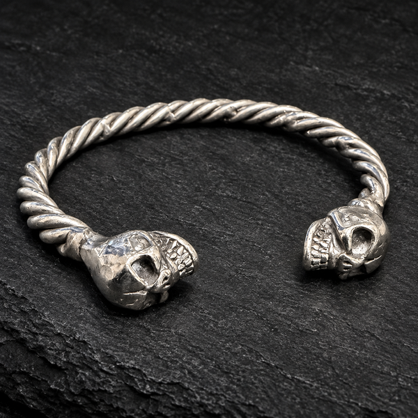 Bracelet jonc torsadé et deux têtes de mort sur fond sombre