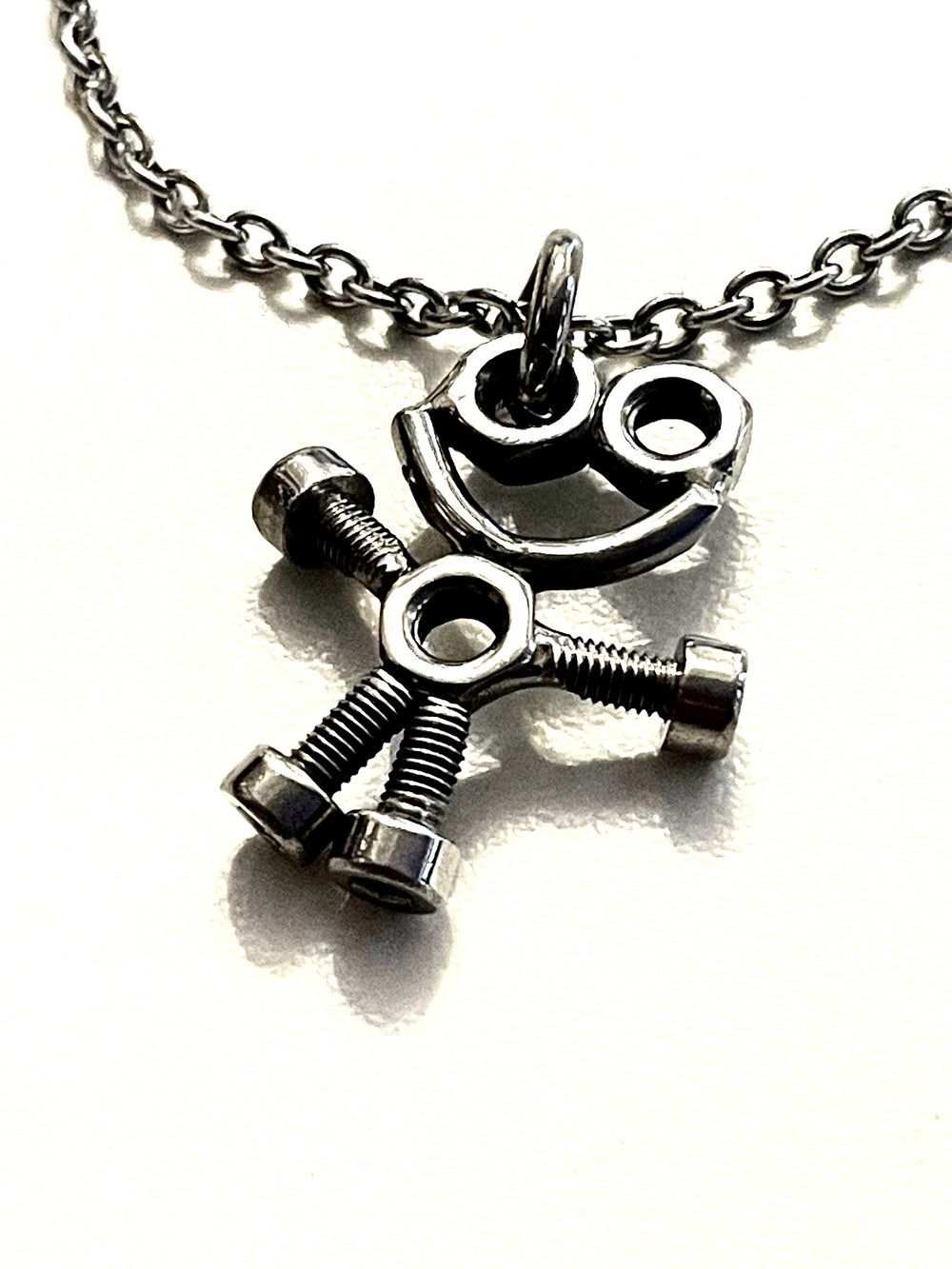 Collier avec pendentif bonhomme souriant, yeux et corps en écrous, bras et jambes en boulons — photographie originale