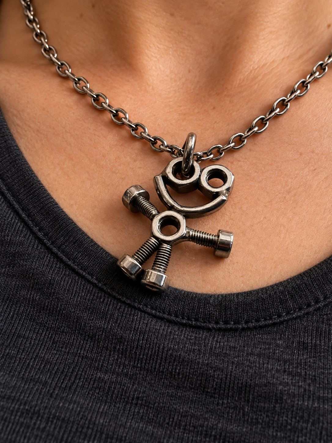 Mise en situation du collier bonhomme en écrous et boulons, porté avec un haut sombre